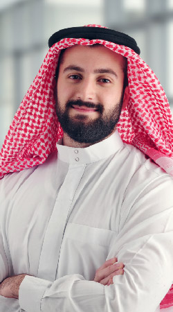 "Person in white thobe and red-checkered ghutrah standing confidently, truck rental Dubai recovery truck services