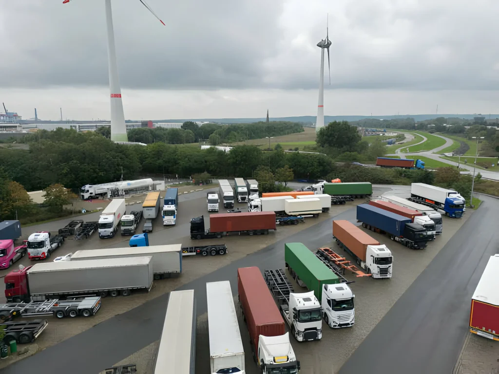 1 ton vs 3 ton truck. Aerial view of a busy transportation hub with colorful cargo trucks lined up under an overcast sky, About Us | Trucking Company in UAE.