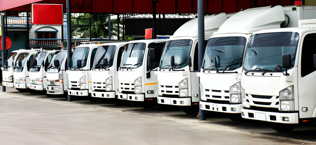 A row of white buses parked in a lot under a red shelter on a sunny day, lined up neatly, showcasing organized and reliable truck service Dubai offerings. also furniture shifting Dubai.