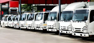 1 ton vs 3 ton truck. A row of white buses parked neatly under a red shelter on a sunny day, representing organized and reliable truck for rent services in Dubai, also suitable for furniture shifting Dubai.