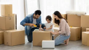 A family of three unpacking boxes in a bright room, preparing for a move, illustrating what to pack first when moving with Drivelo’s truck rental support.